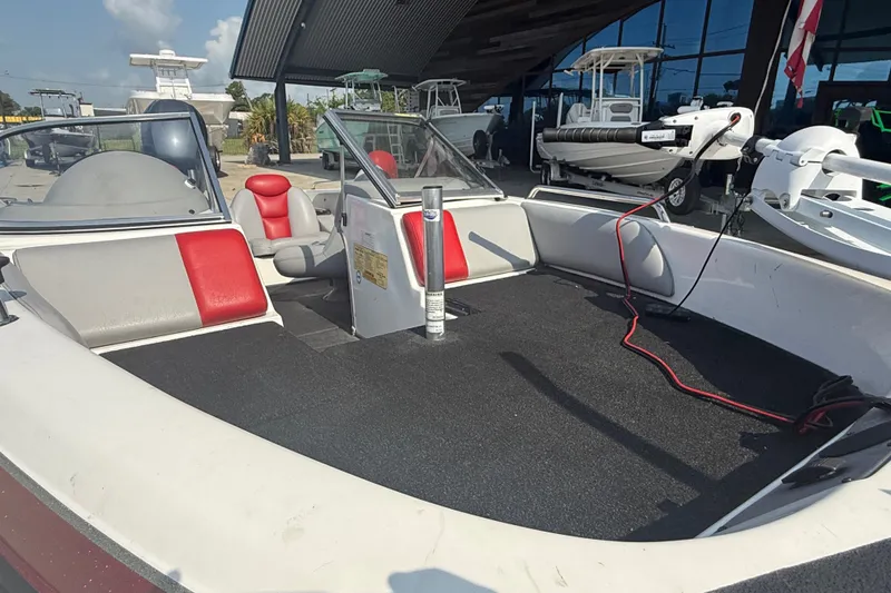 Slide: The Image of 2006 Skeeter SL 190 boat interior with red and gray seating, docked outdoors. - 15