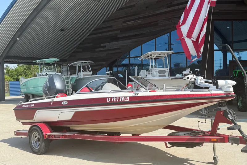 Slide: The Image of 2006 Skeeter SL 190 boat on trailer, parked outside a showroom with American flag. - 2