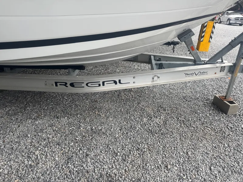 Slide: The Image of A 2015 Cobalt 296 boat on a Regal trailer, parked on a gravel lot. - 3