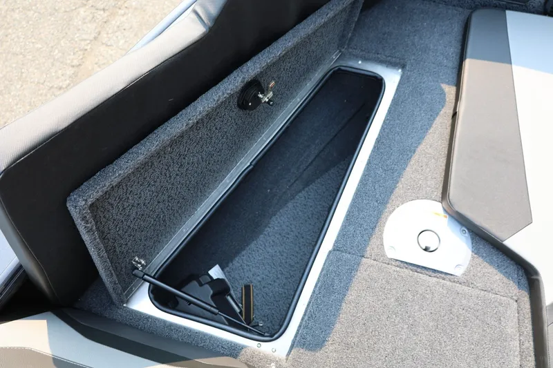 Slide: The Image of An open storage compartment in a boat with gray carpeting and a black hydraulic arm. - 18