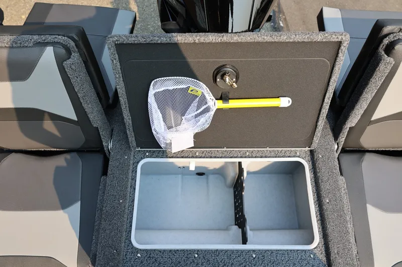 Slide: The Image of The image shows the storage compartment of a Lund 1875 Crossover XS boat with a net and yellow tool. - 45
