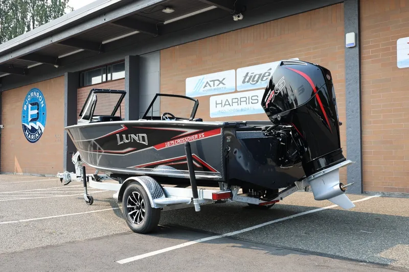 Slide: The Image of Lund 1875 Crossover XS 2027: A modern motorboat on a trailer, parked in front of a building. - 4
