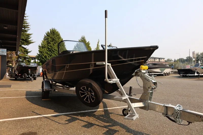 Slide: The Image of A Lund 1875 Crossover XS boat on a trailer, parked in a lot next to other boats. - 10