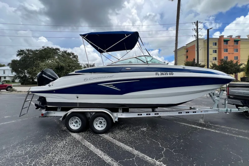 Slide: The Image of 2023 Crownline Eclipse E235 XS boat on trailer, parked outdoors under cloudy sky. - 52