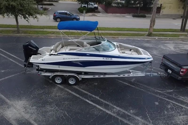 The Image of 2023 Crownline Eclipse E235 XS boat on trailer, blue canopy, parked in lot. - 20