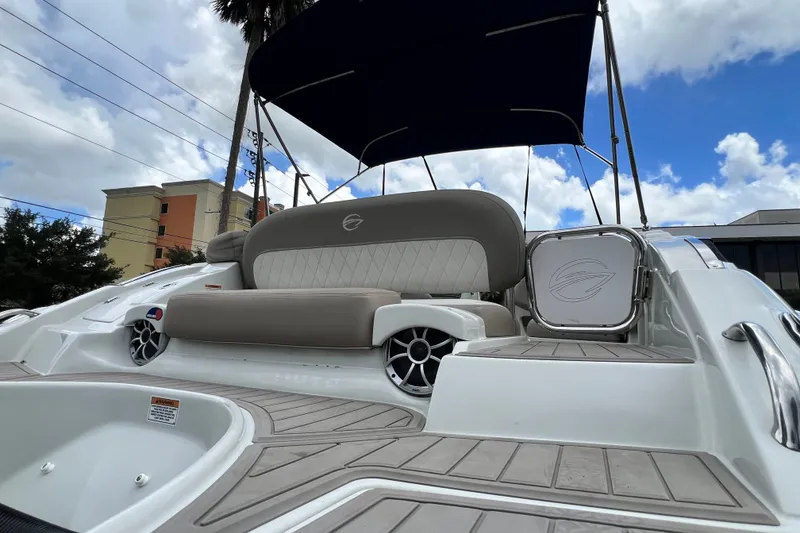 Slide: The Image of 2023 Crownline Eclipse E235 XS boat with cushioned seating and canopy under a blue sky. - 49