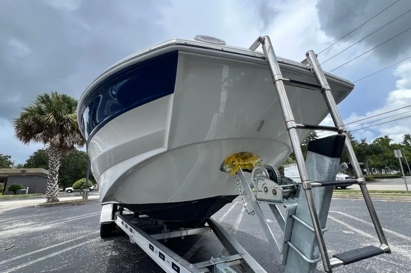 Slide: The Image of 2023 Crownline Eclipse E235 XS boat on trailer, under cloudy sky, with ladder. - 33