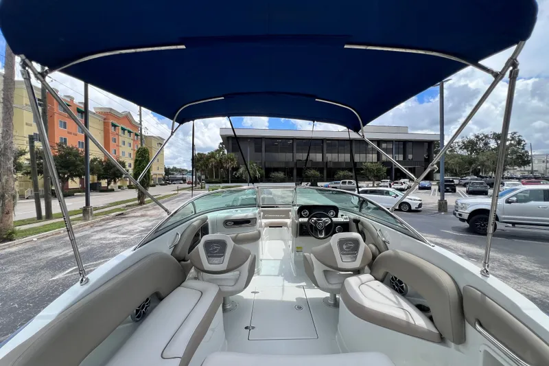 Slide: The Image of 2023 Crownline Eclipse E235 XS boat interior with canopy, parked in urban setting. - 55