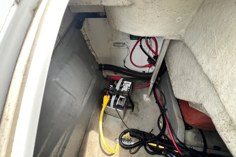 Slide: The Image of 2023 Crownline Eclipse E235 XS boat battery compartment with wiring and cables. - 58