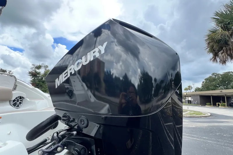 Slide: The Image of 2023 Crownline Eclipse E235 XS with Mercury outboard motor, parked outdoors under cloudy sky. - 40