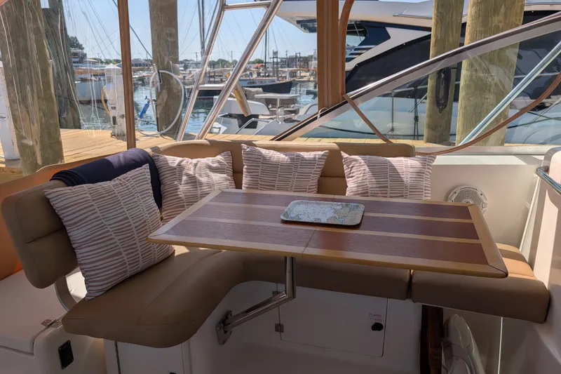 Slide: The Image of Cozy seating area on 2000 Pursuit 3400 Express yacht with striped cushions and wooden table. - 18