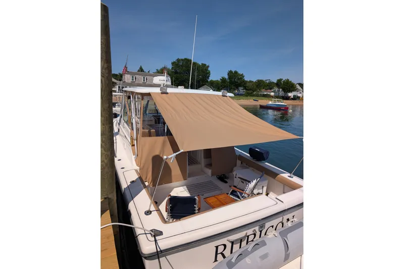 Slide: The Image of 2000 Pursuit 3400 Express boat docked with sunshade, calm waters, and scenic background. - 31
