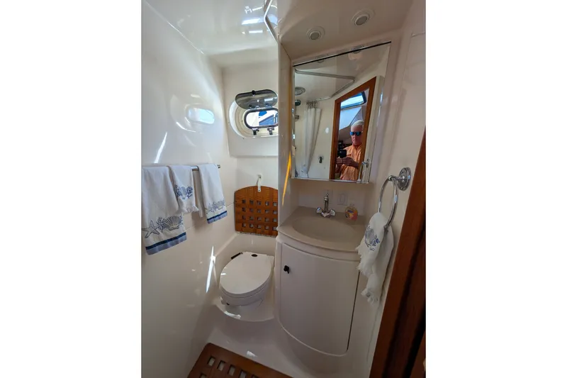 Slide: The Image of Bathroom interior of 2000 Pursuit 3400 Express boat, featuring sink, mirror, and porthole window. - 13