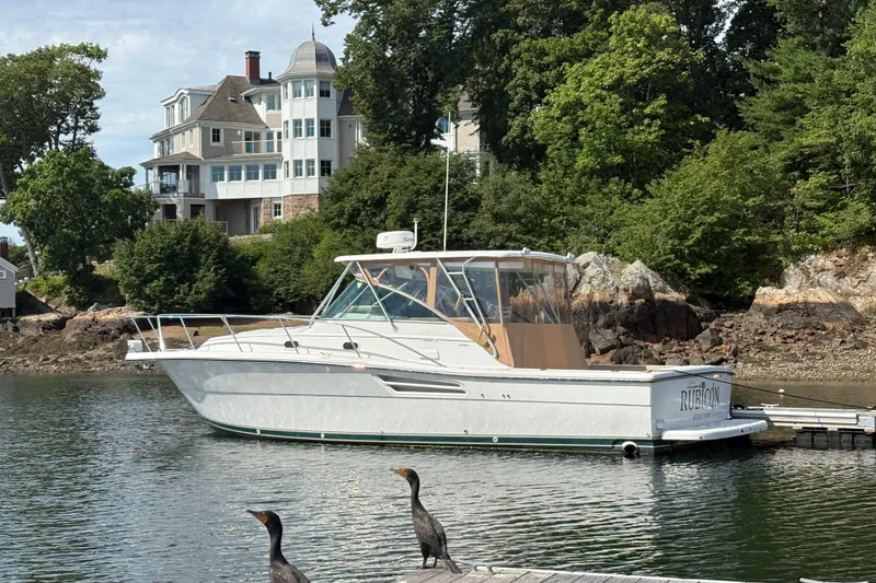 Slide: The Image of 2000 Pursuit 3400 Express boat docked near a luxurious waterfront home. - 3