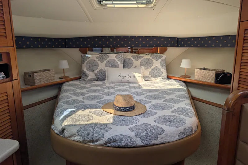Slide: The Image of Cozy cabin interior of 2000 Pursuit 3400 Express with patterned bedding and straw hat. - 6