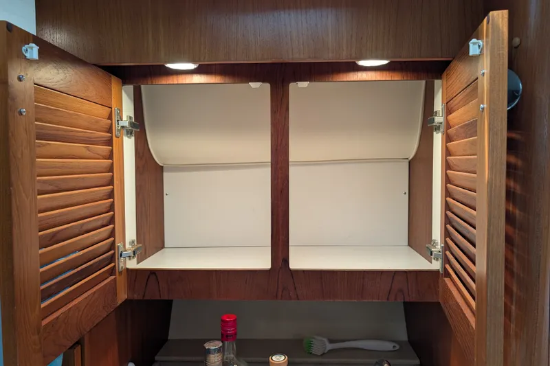 Slide: The Image of Open wooden cabinet with louvered doors on a 2000 Pursuit 3400 Express boat. - 48