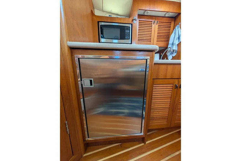 Slide: The Image of Wooden yacht interior with stainless steel fridge, microwave, and cabinets. Pursuit 3400 Express, 2000 model. - 10