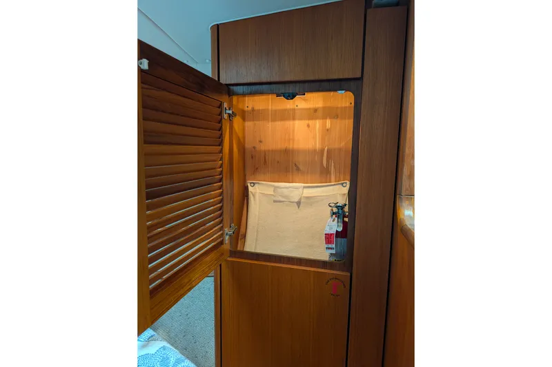 Slide: The Image of Wooden cabinet interior with fire extinguisher on a 2000 Pursuit 3400 Express boat. - 51