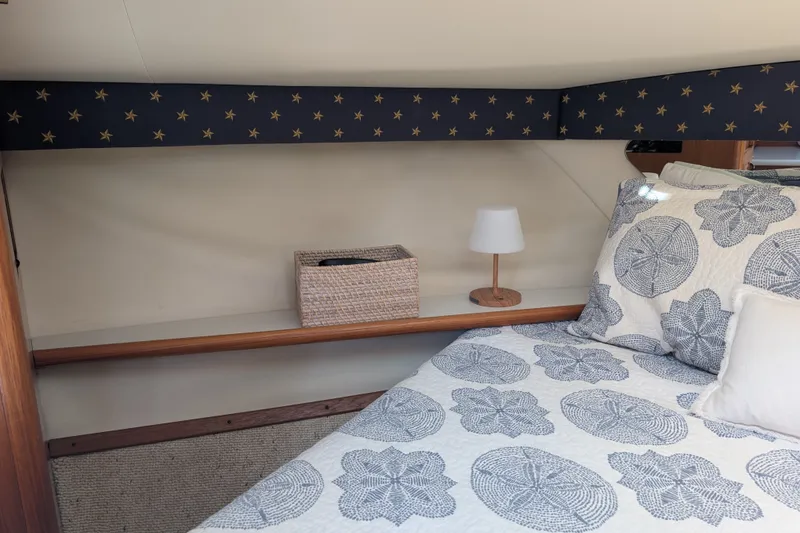 Slide: The Image of Cozy cabin interior of 2000 Pursuit 3400 Express with nautical-themed bedding and decor. - 8