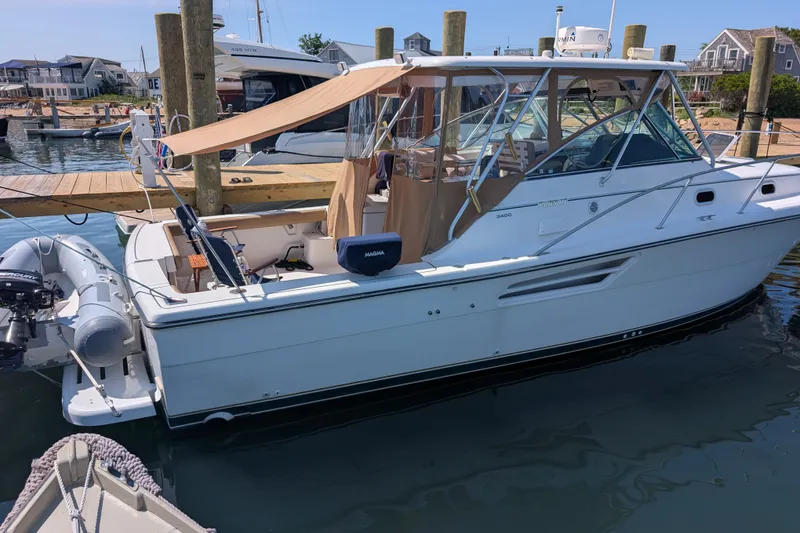 Slide: The Image of 2000 Pursuit 3400 Express boat docked at marina with canopy and inflatable dinghy. - 29