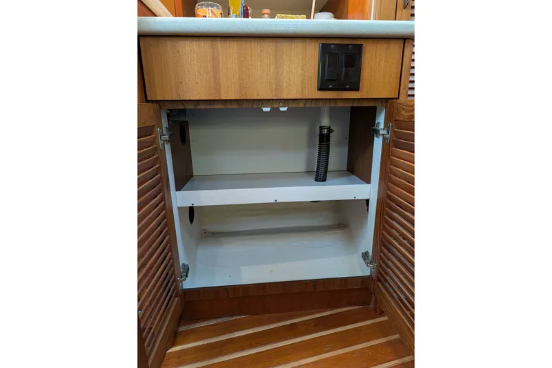 Slide: The Image of Open wooden cabinet under sink in 2000 Pursuit 3400 Express boat. - 52