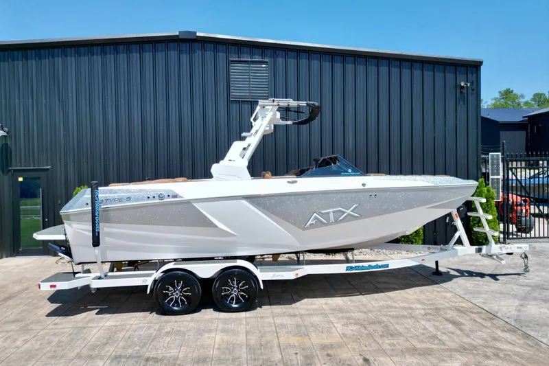 The Image of 2027 ATX Surf Boats 22 Type-S on trailer, parked outside a black building. - 1