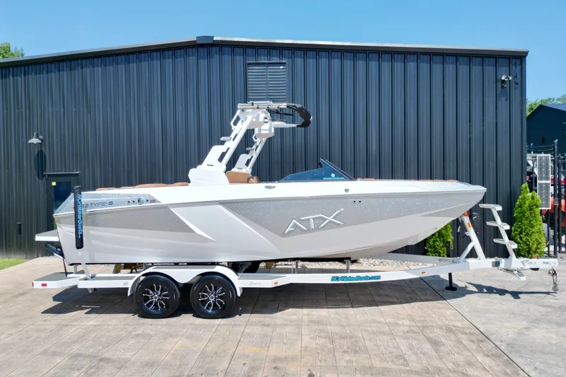 Slide: The Image of 2027 ATX Surf Boats 22 Type-S on trailer, parked outside a black building. - 2