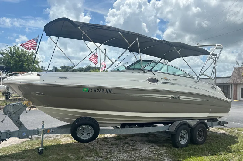 Slide: The Image of 2006 Sea Ray 240 Sundeck boat on trailer with canopy, parked outdoors. - 14