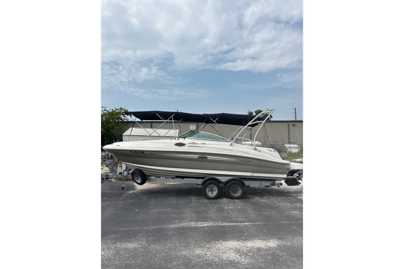 Slide: The Image of 2006 Sea Ray 240 Sundeck boat on trailer, parked outdoors under cloudy sky. - 26