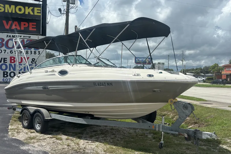Slide: The Image of 2006 Sea Ray 240 Sundeck boat on trailer, parked outdoors under cloudy sky. - 6