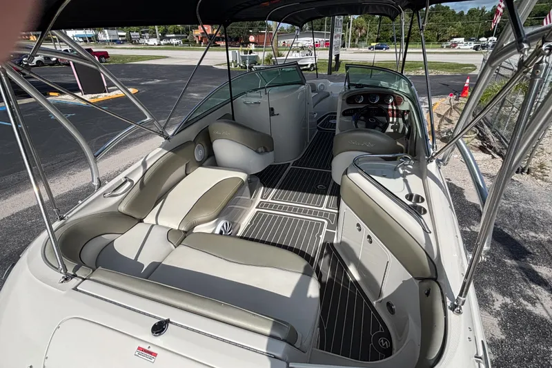 Slide: The Image of 2006 Sea Ray 240 Sundeck boat interior with seating and dashboard, parked outdoors. - 32