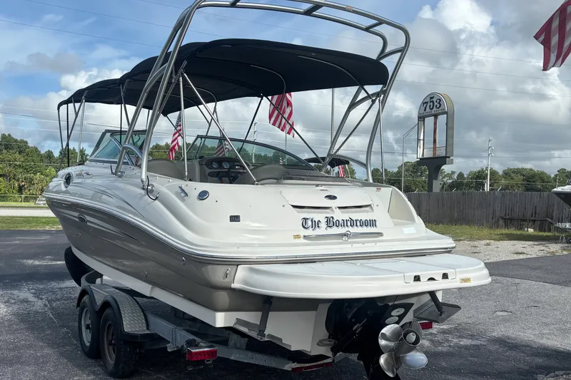 Slide: The Image of 2006 Sea Ray 240 Sundeck boat on trailer, featuring canopy and American flags. - 4