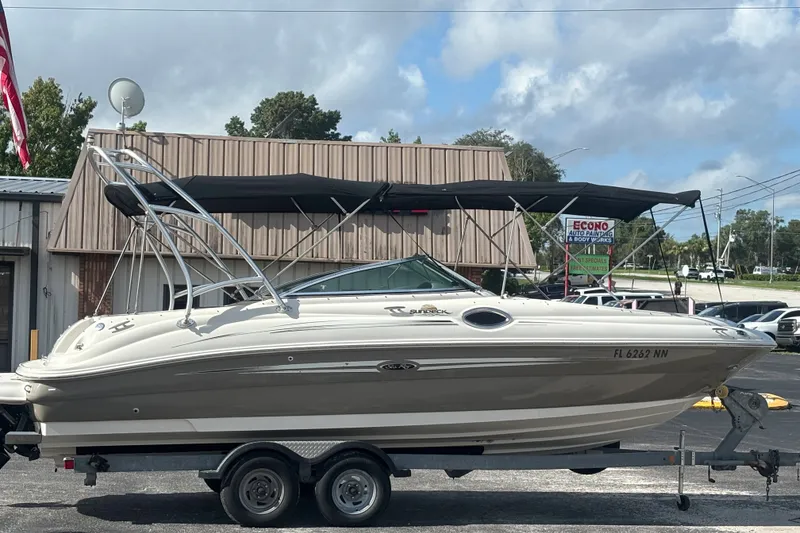 Slide: The Image of 2006 Sea Ray 240 Sundeck boat on trailer, parked outdoors under cloudy sky. - 3