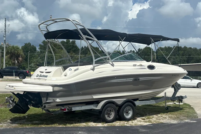 Slide: The Image of 2006 Sea Ray 240 Sundeck boat on trailer, parked outdoors under cloudy sky. - 1