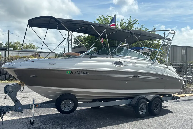 The Image of 2006 Sea Ray 240 Sundeck boat on trailer, featuring a sleek design and canopy. - 0
