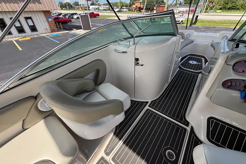 Slide: The Image of 2006 Sea Ray 240 Sundeck interior with seating and dashboard, parked in a lot. - 39