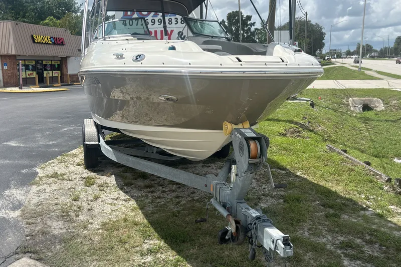 Slide: The Image of 2006 Sea Ray 240 Sundeck boat on trailer, parked near a store. - 48