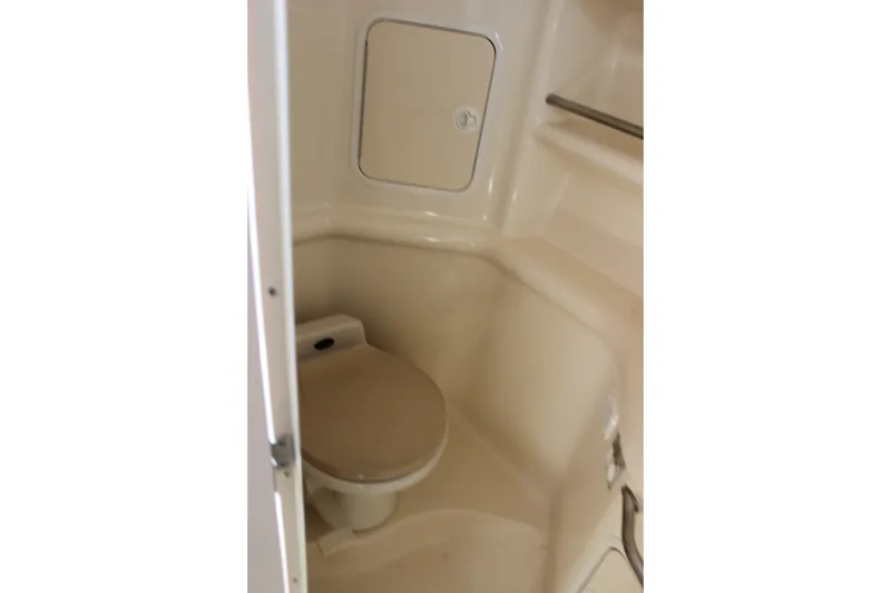Slide: The Image of Compact bathroom in 2000 Sea Ray Sundancer 310 boat, featuring a toilet and storage compartment. - 27