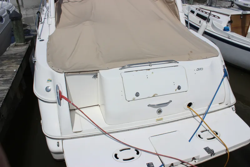Slide: The Image of 2000 Sea Ray Sundancer 310 docked, covered with beige tarp, showing rear view. - 31