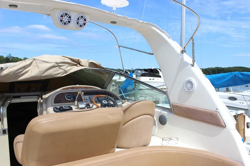 Slide: The Image of 2000 Sea Ray Sundancer 310 cockpit with beige seating and control panel, docked at marina. - 5