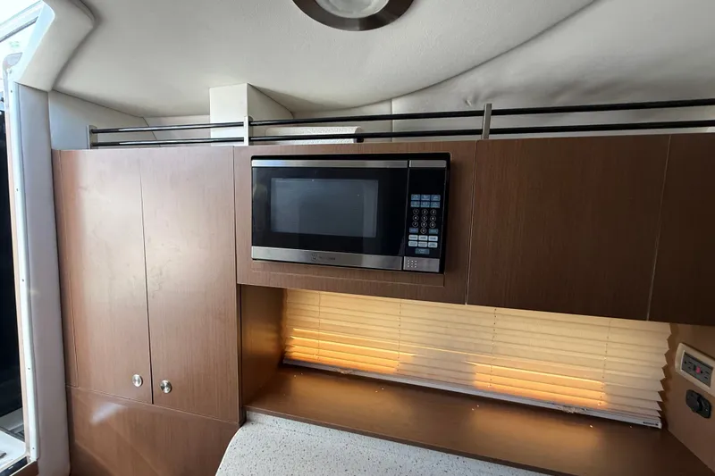 Slide: The Image of 2012 Sea Ray Sundancer 310 interior with microwave and wooden cabinetry. - 27