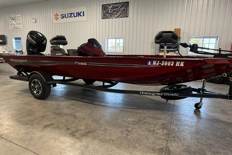 The Image of 2021 Ranger RT188 boat in showroom, red color, on trailer, Suzuki banner in background. - 1
