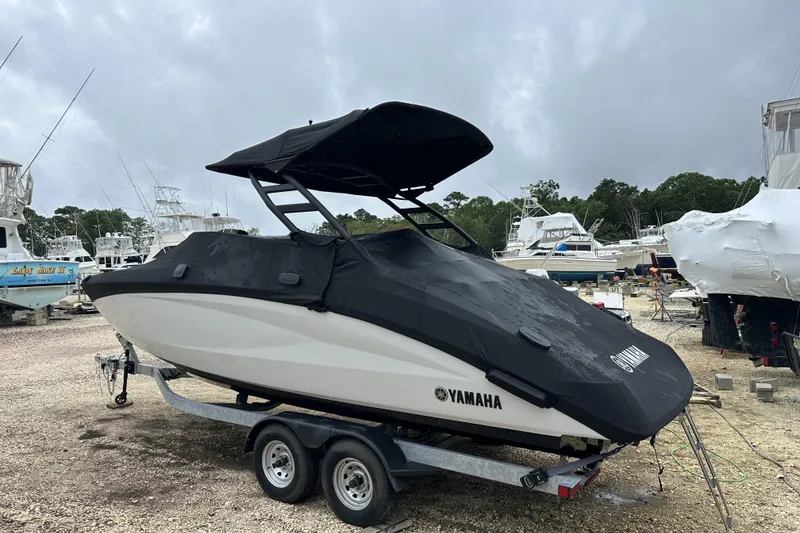 Slide: The Image of 2025 Yamaha Boats 252SD on trailer, covered, in a marina with other boats. - 16