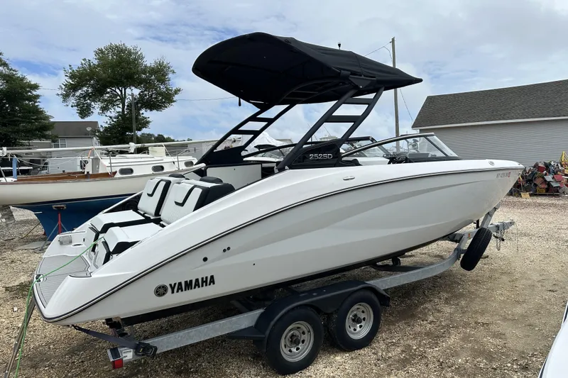 The Image of 2025 Yamaha Boats 252SD on trailer, sleek design, black canopy, parked outdoors. - 0