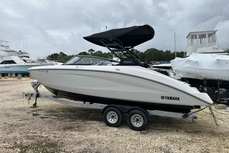 Slide: The Image of 2025 Yamaha Boats 252SD on trailer, parked outdoors with other boats. - 4