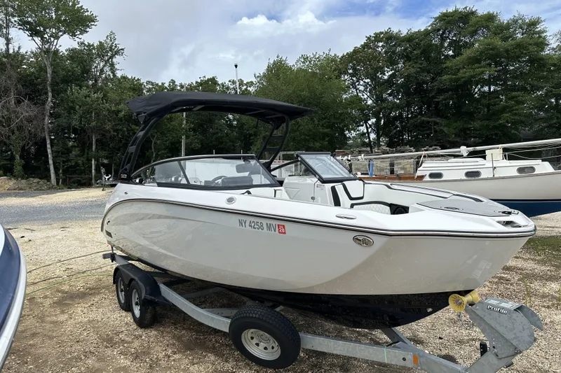 Slide: The Image of 2025 Yamaha Boats 252SD on trailer, parked outdoors with trees in background. - 2