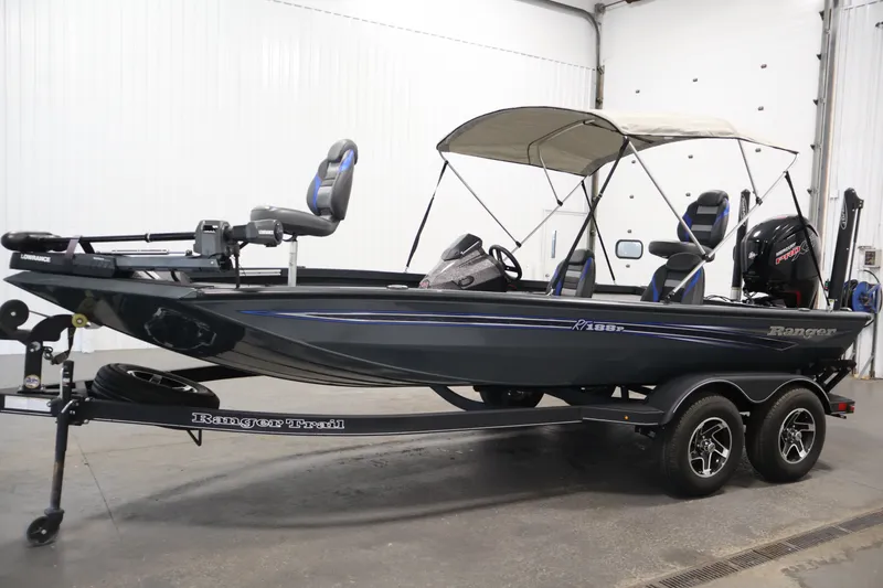 Slide: The Image of 2023 Ranger RT188P fishing boat with canopy, trailer, and motor in a garage setting. - 8