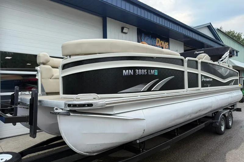 Slide: The Image of 2016 Premier 270 Intrigue RF pontoon boat on trailer, parked outside a building. - 2