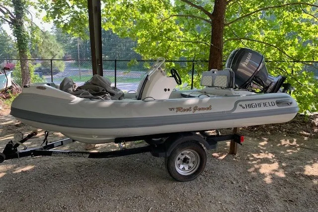 The Image of 2026 Highfield Sport 390 inflatable boat on trailer, parked outdoors under trees. - 0