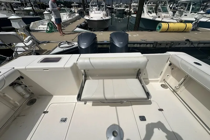 Slide: The Image of 2013 Pursuit OS 345 Offshore boat interior with seating and dual engines at marina. - 26